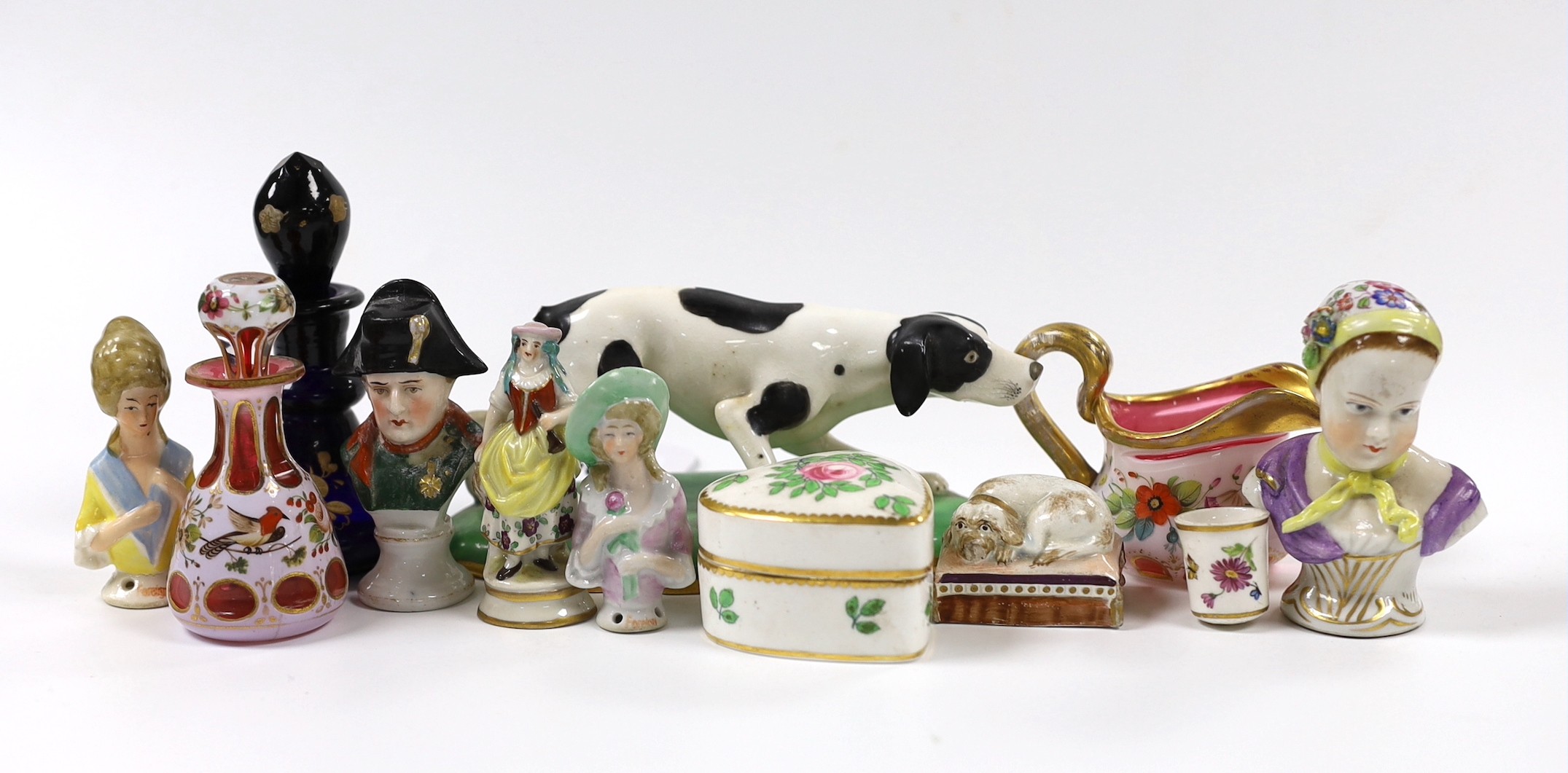 An early 19th century earthenware sleeping dog, a Victorian bone china model of a dog, a miniature overlaid glass decanter and ewer, etc. (12)
